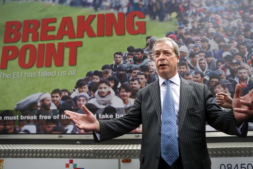 Nigel Farage stands in front of a large billboard with the words Breaking Point and an image of immigrants.