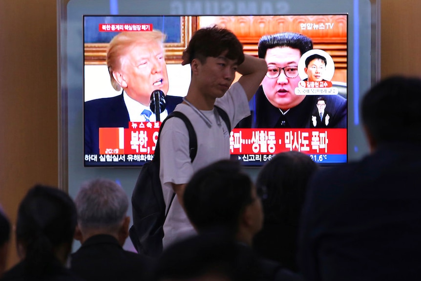People watch a TV screen showing file footage of US President Donald Trump and North Korean leader Kim Jong-un