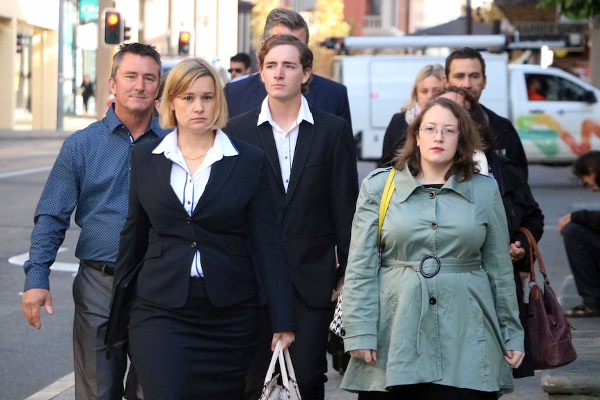 Joel Payne walks down the street flanked by a man and two women.