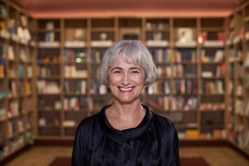 Smiling woman stands in front of bookcase