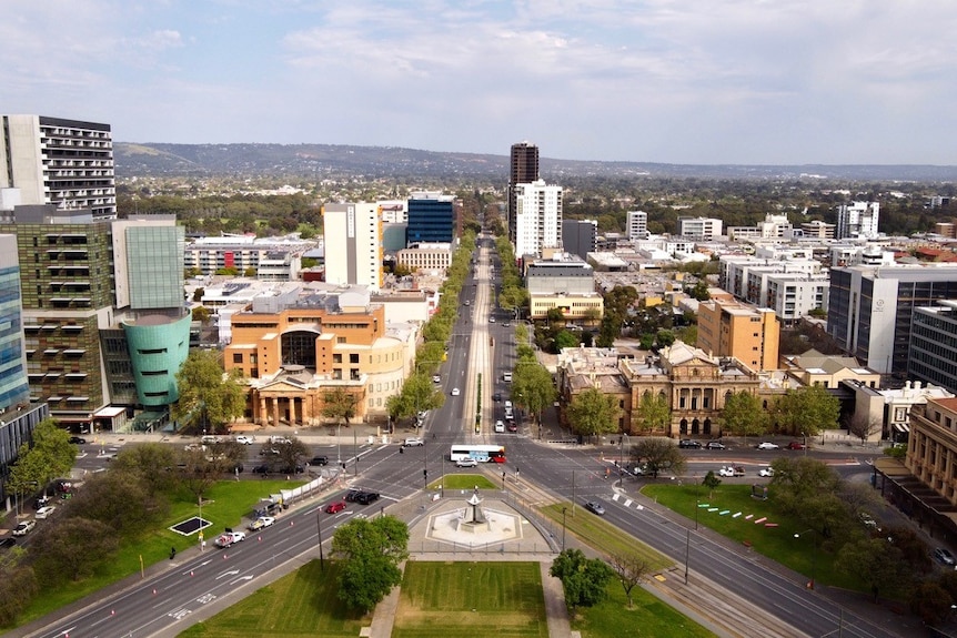 A shot of Adelaide's CBD taken by drone, with a park in the foreground, buildings behind and hills in the background.
