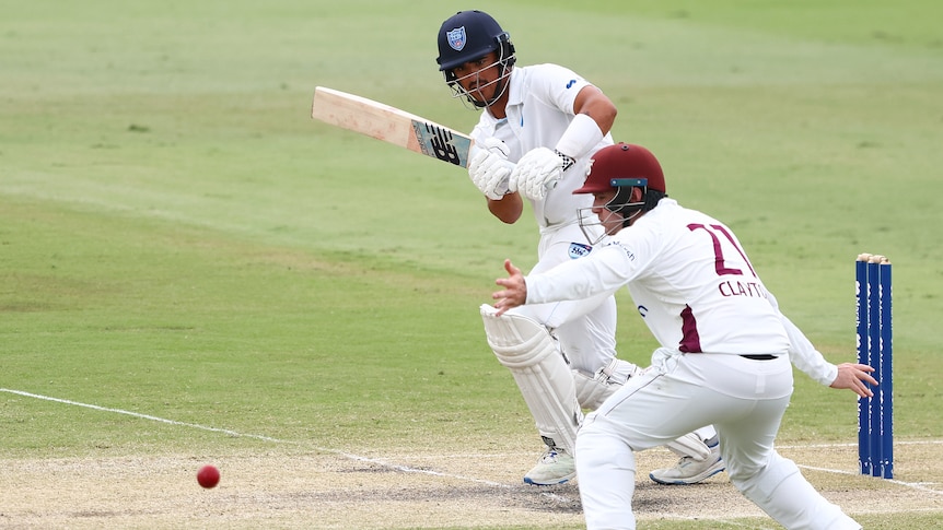 A NSW batter clips the ball on the leg side past a Queensland fielder in a Sheffield Shield match.