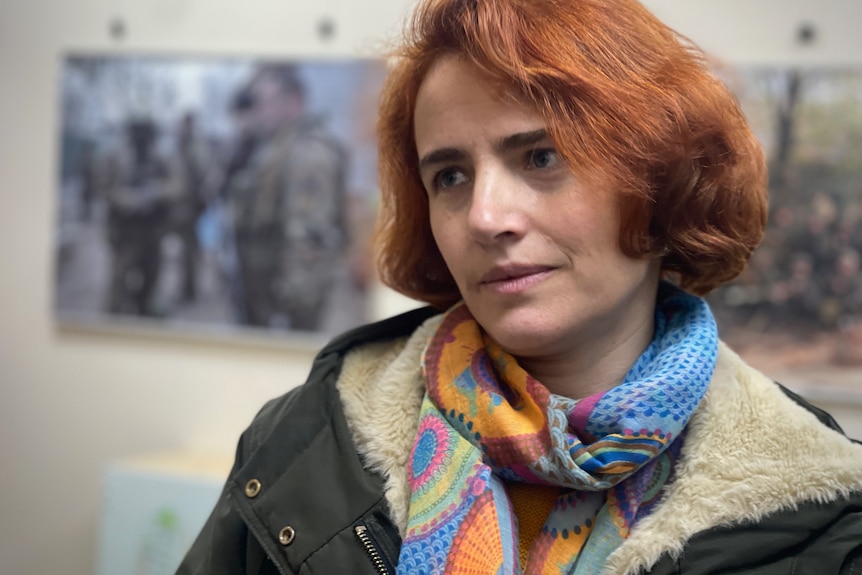 A woman with red hair and wearing a multi-coloured scarf and coat