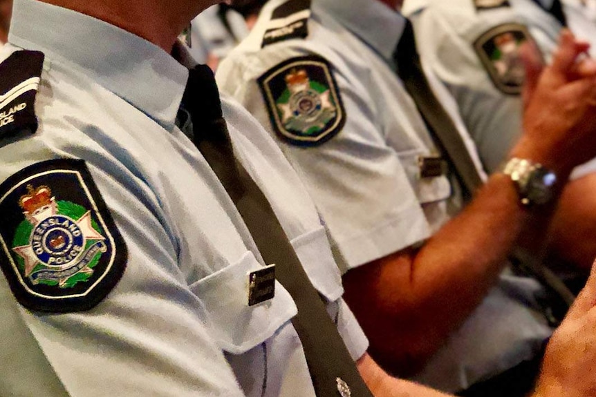 Row of police officers clapping as they sit at a press conference.