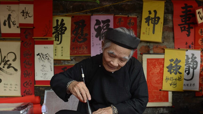 A calligrapher writes down best wishes for the lunar new year for customers outside the Temple of Literature in Hanoi.