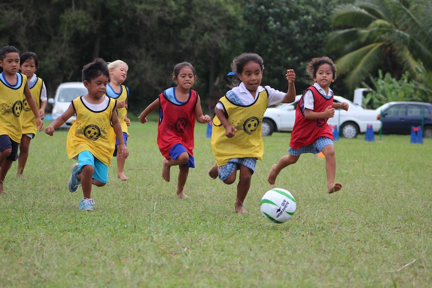 Girls and boys run after a soccer ball
