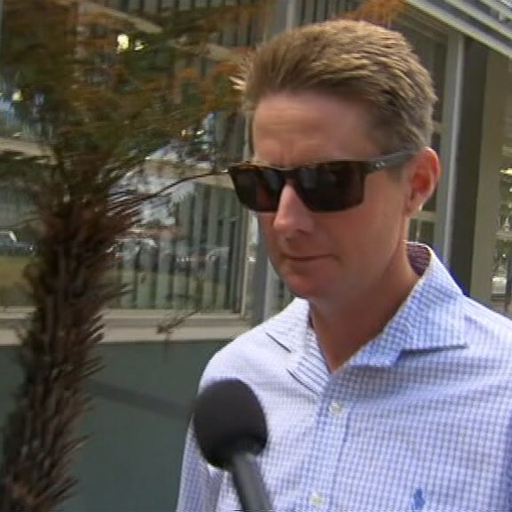 A reporter who is not visible points a microphone at Jarrod McLean as he arrives at Racing Victoria's headquarters.