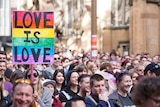 People hold coloured signs in a large crowd in support of same-sex marriage.