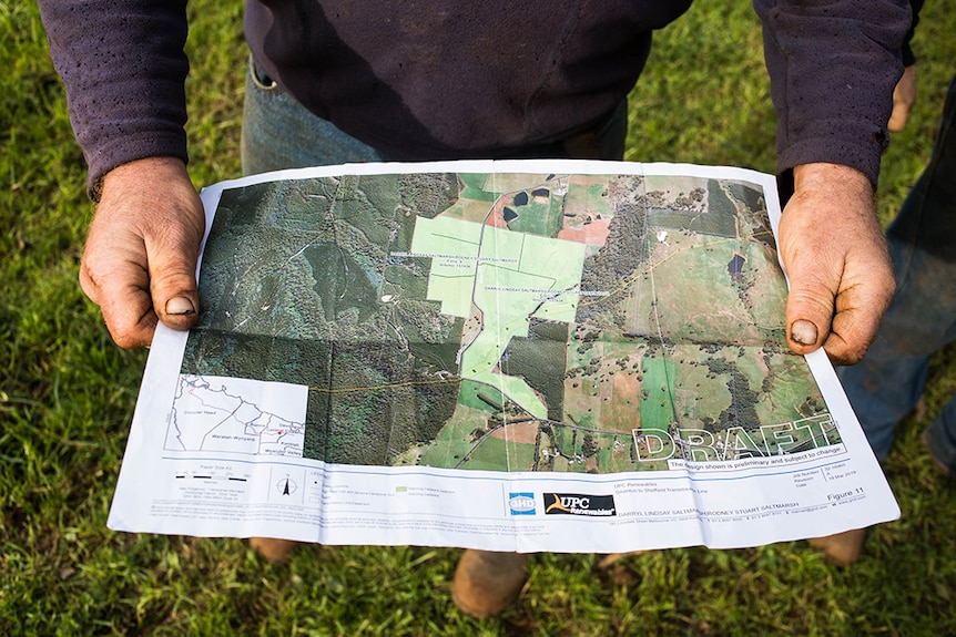 One of the Saltmarsh brothers holds a map of the planned UPC across their Tasmanian property.