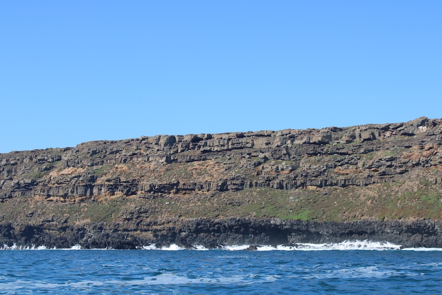 A cliff extends above the ocean.