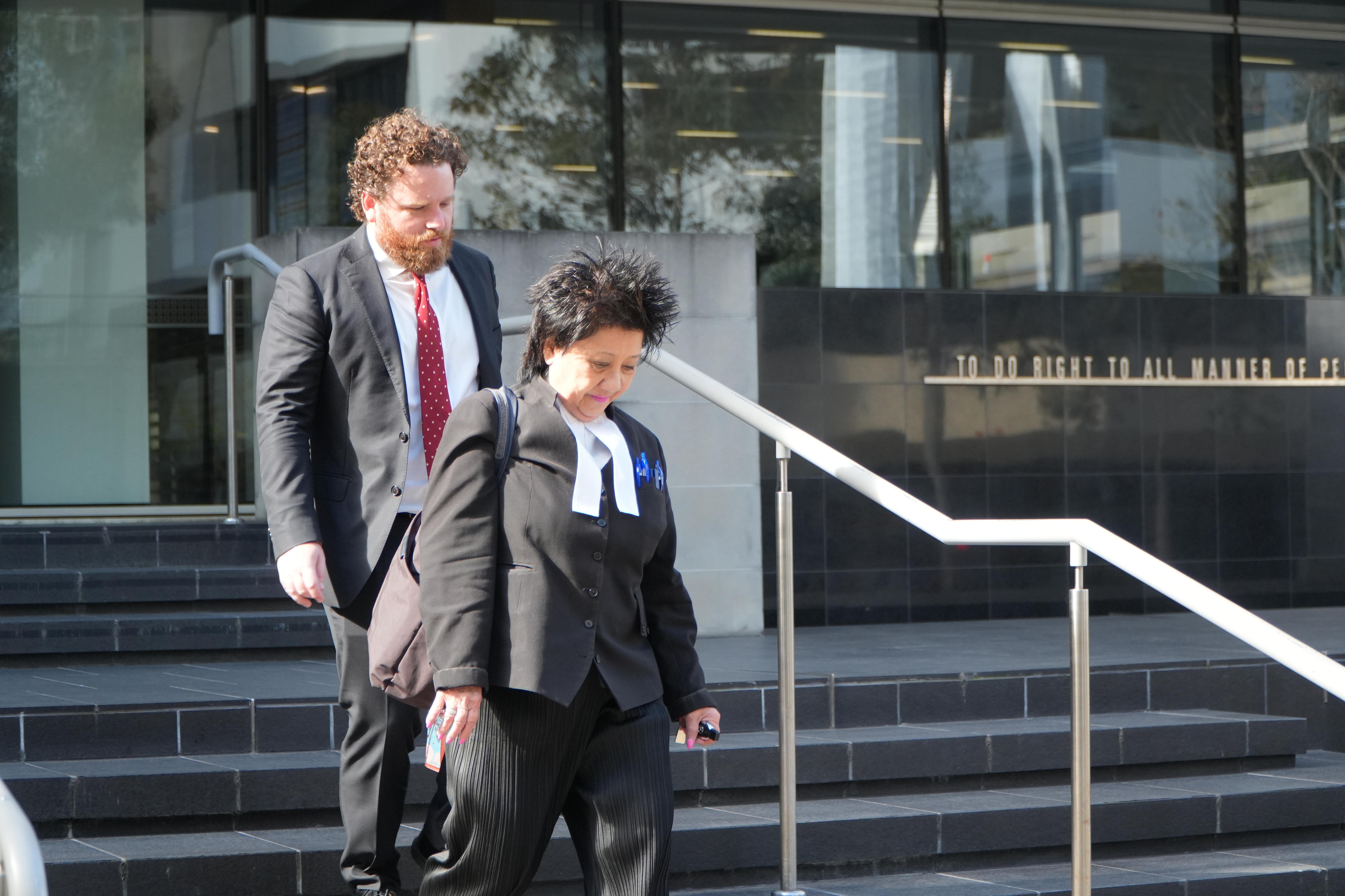 A female lawyer wearing a gown leaves a court building.