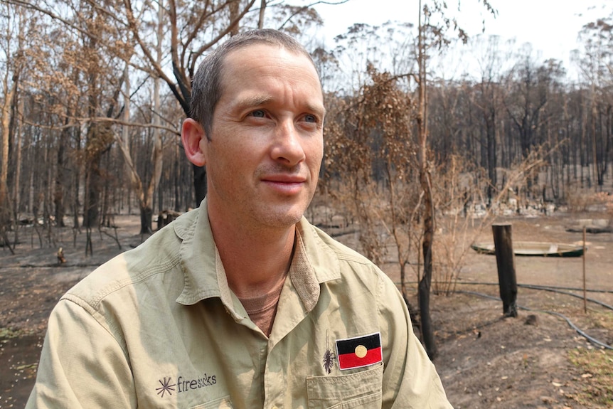 A man in a burnt out area of bush