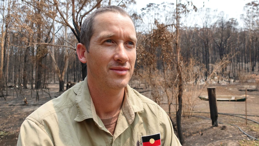 A man in a burnt out area of bush