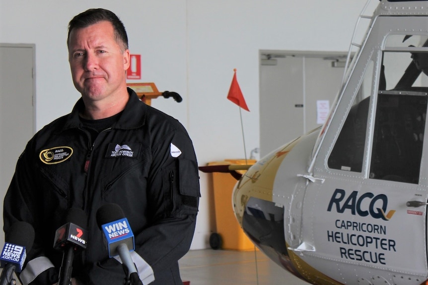 Todd Simpson, RACQ helicopter crew member, helicopter behind.