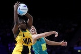 An Australian netball player and a Jamaican player jump for the ball in the Commonwealth Games gold medal match.