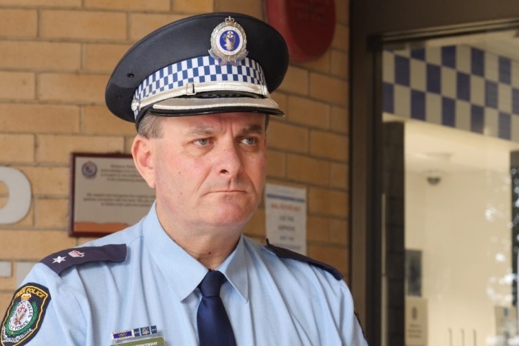 A police district commander wearing his official hat and looking stern outside a police station