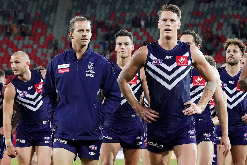 A group of Fremantle Dockers players led by captain Nat Fyfe and Matt Taberner leave the field after a loss.