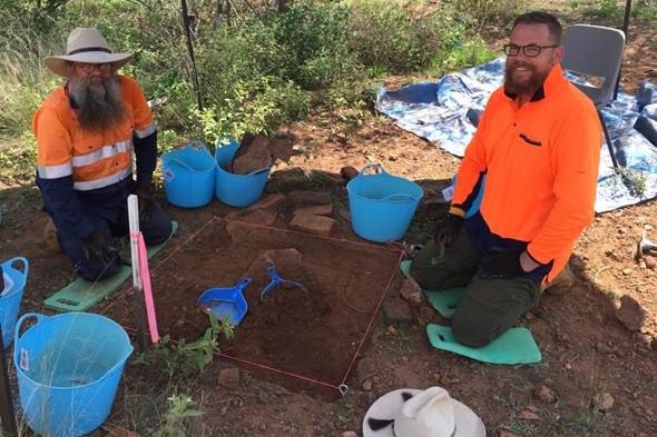 Two men in high-vis digging the earth.