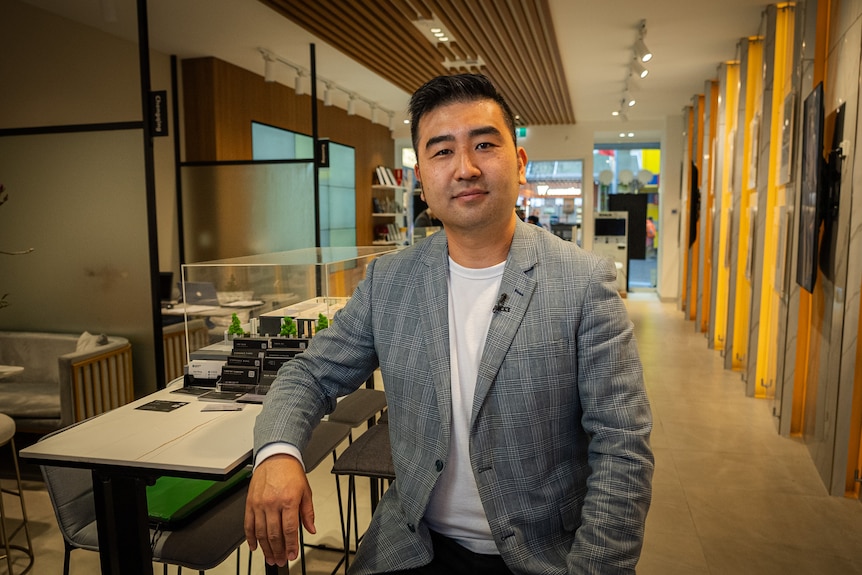 A middle aged man of Asian appearance sits in the empty foyer of an office.