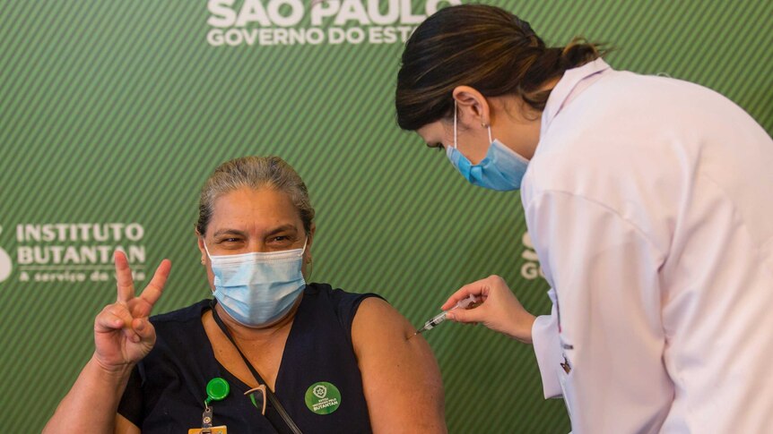 A Brazilian woman celebrates as she gets her shot of the COVID-19 vaccine