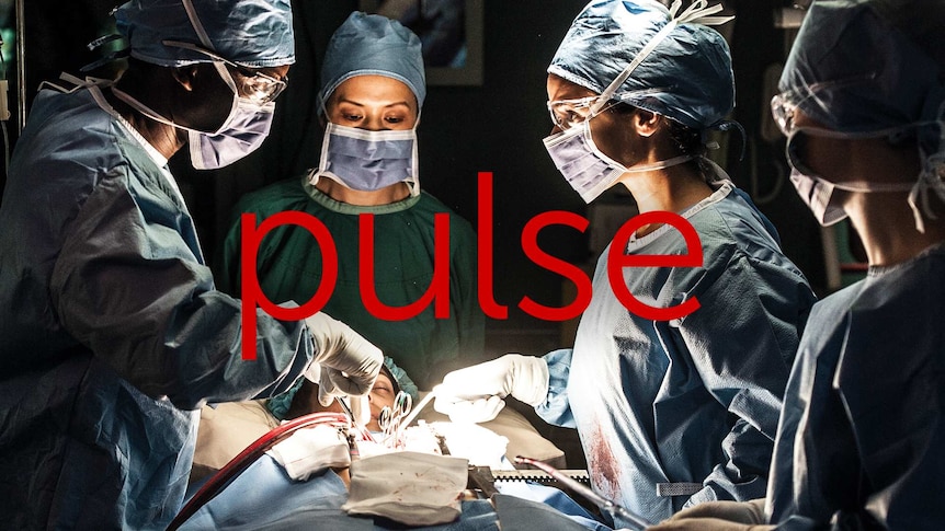 Four medical professionals in operating theatre working on a patient