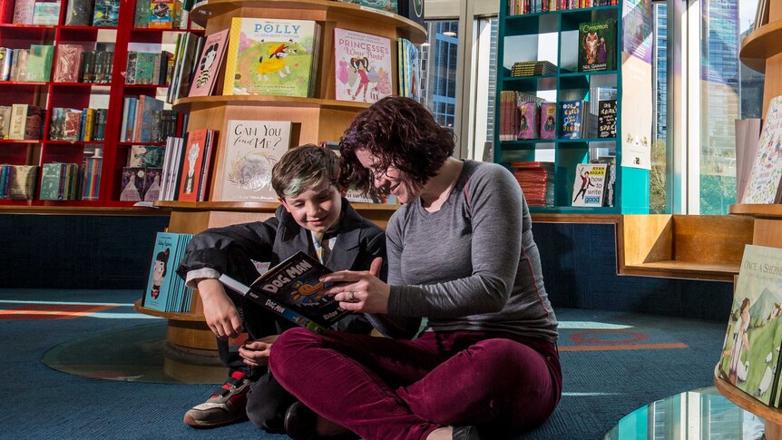 Colour photograph of a son and mother reading in a children's book store.