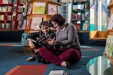 Colour photograph of a son and mother reading in a children's book store.