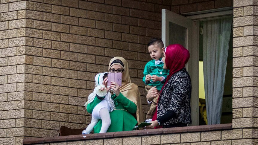 A woman takes a photo of the crowds of Muslims outside Lakemba Mosque