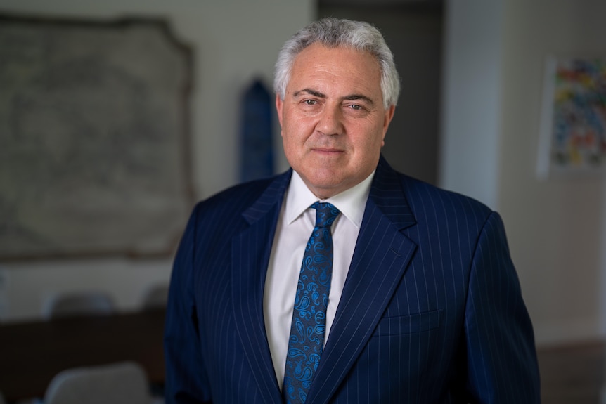 A man with grey hair wearing a suit stands for the camera.