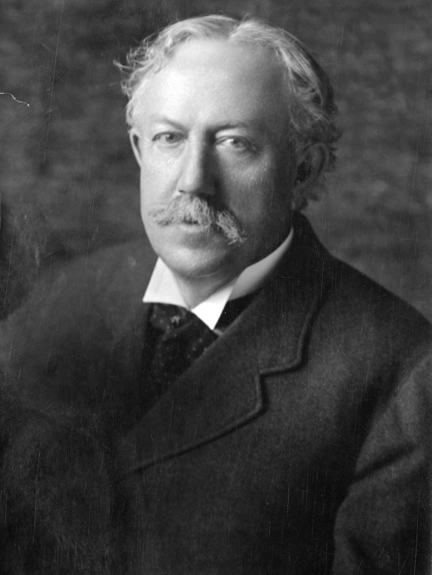 An old black and white photo of an older man with white hair and a moustache