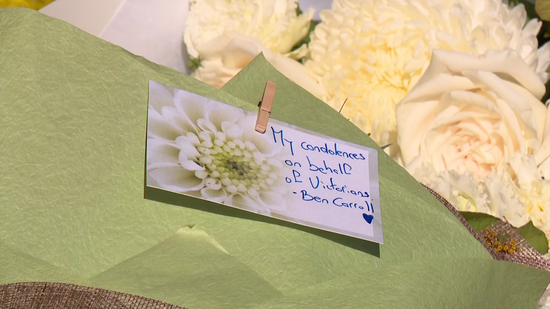 A white card with a picture of a flower and the words "My condolences on behalf of Victoria - Ben Carroll".
