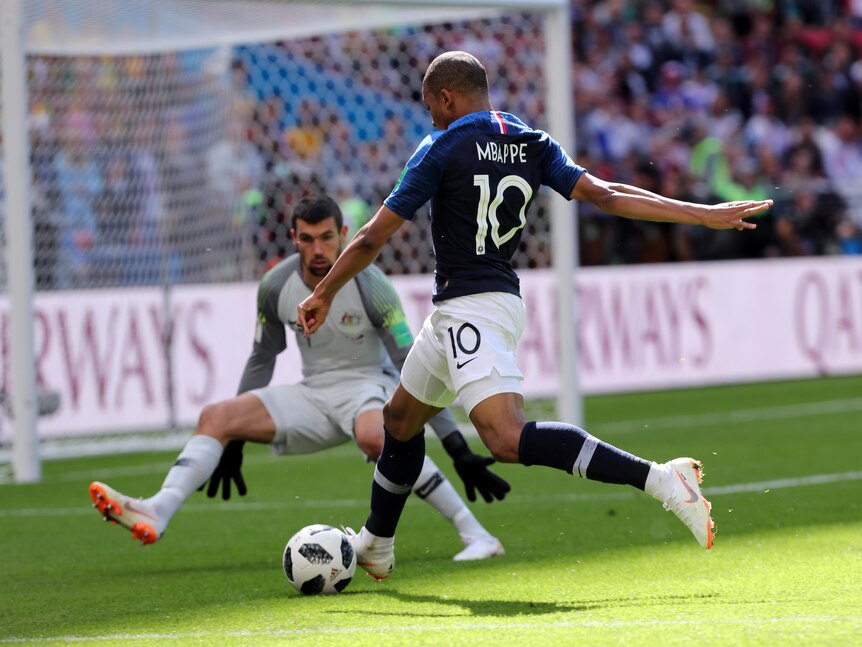 Le Français Kylian Mbappe regarde le ballon alors qu'il se prépare à tirer et le gardien australien s'écarte. 