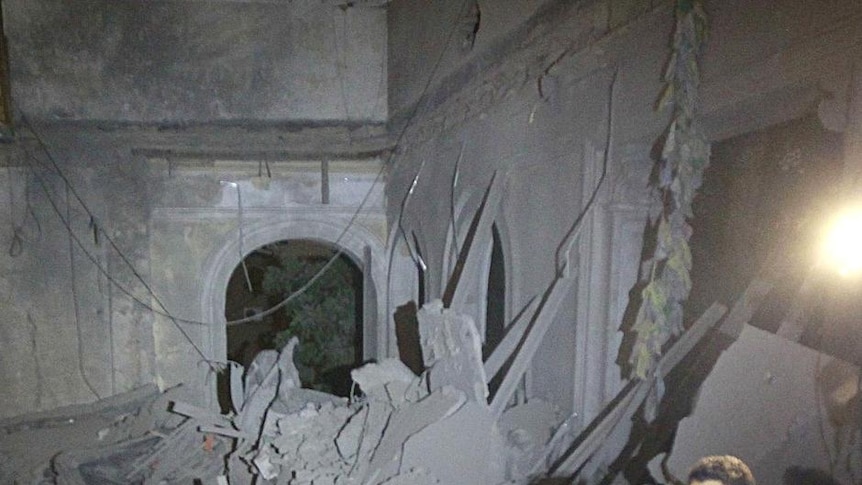 A police officer looks at a damaged building at the High Commission for Children in Tripoli