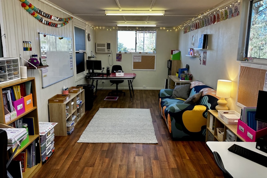 a room set up as a classroom with a couch, chair, desk, decorations 