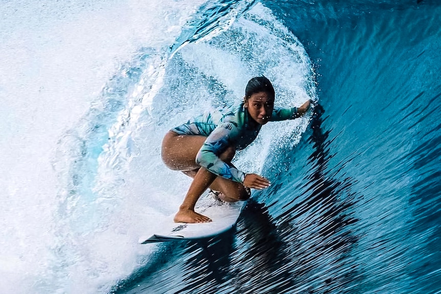A woman surfs in the curl of a large wave.