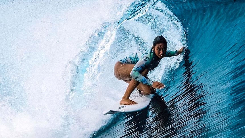 A woman surfs in the curl of a large wave.