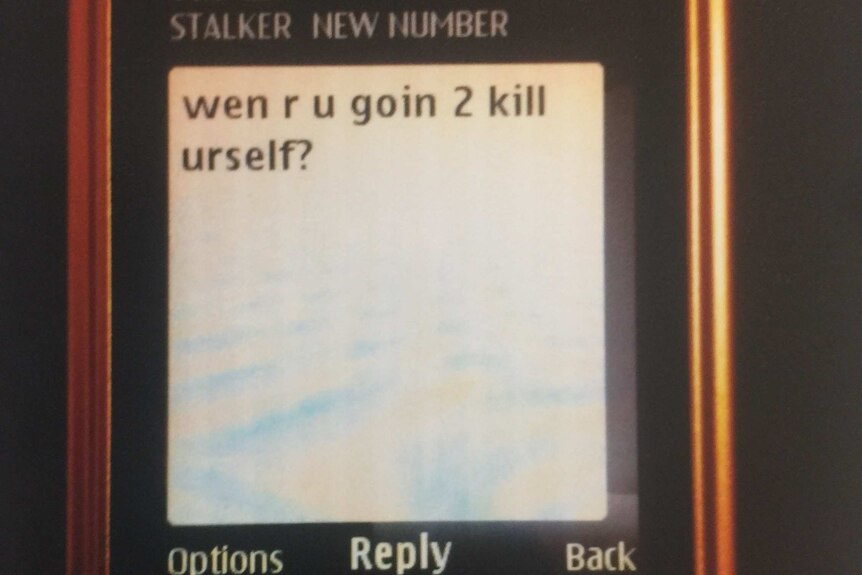 A message on a phone screen says 'wen r u goin 2 kill urself?'