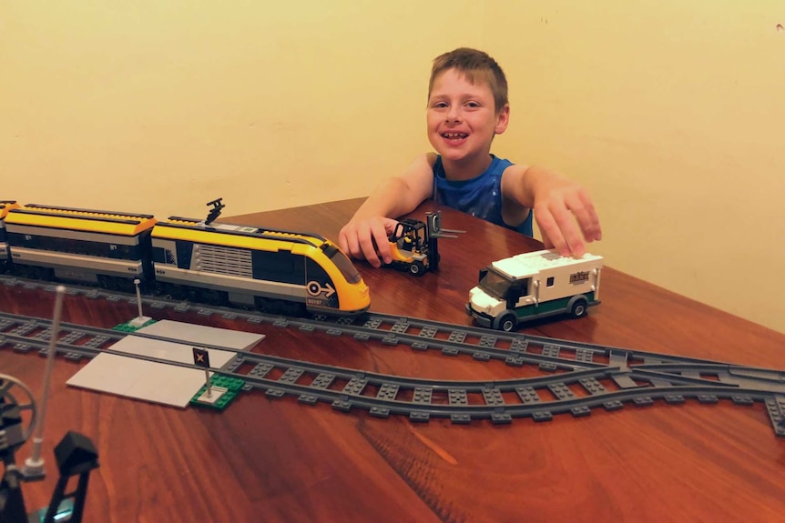 Ezekiel plays with toy trucks and large Lego train he assembled during self-isolation.