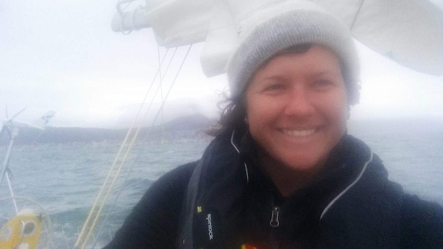 A tight mid shot of a smiling Lisa Blair on her boat as she sails out of Cape Town.