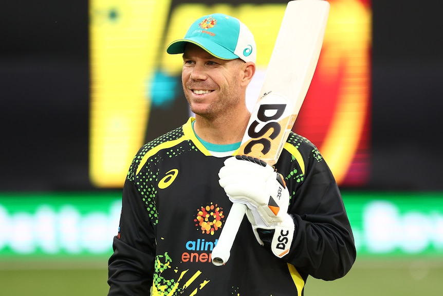 David Warner smiles while resting his cricket bat on his shoulder