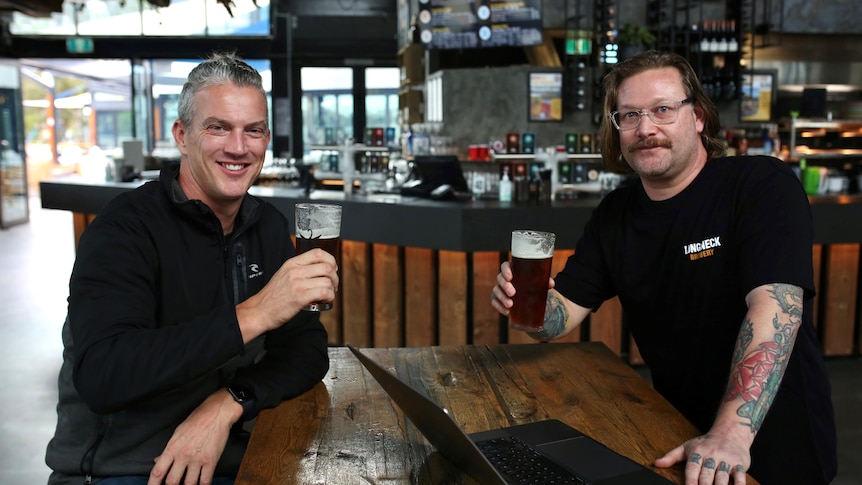 Two men sitting at a brewery with beers