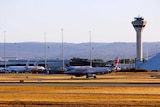A Jetstar aircraft taxies down the runway with Virgin planes in the background at Perth Aiport.