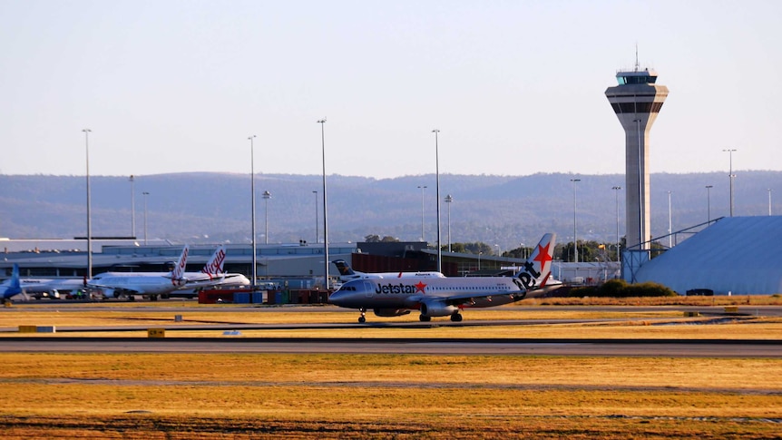 A Jetstar aircraft taxies down the runway with Virgin planes in the background at Perth Aiport.