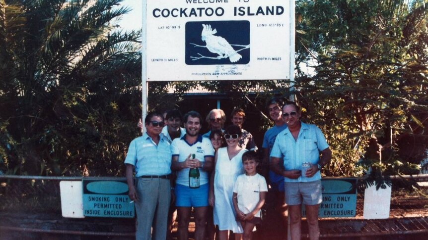 A group of people standing in front of a sign saying Cockatoo Island