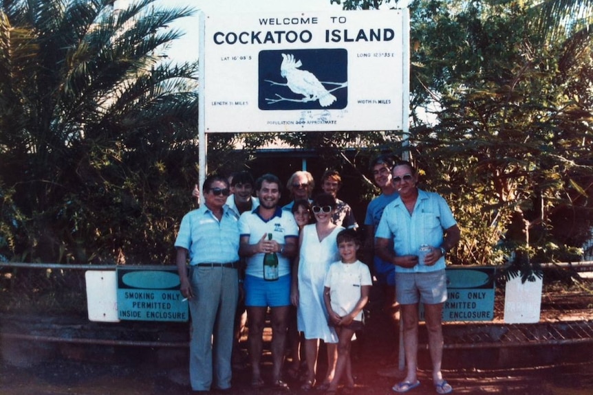 A group of people standing in front of a sign saying Cockatoo Island