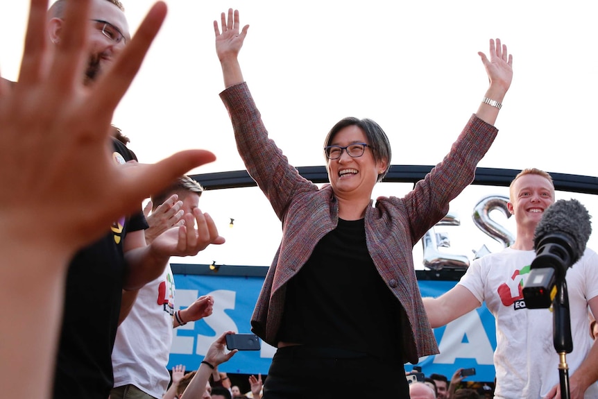 Penny Wong with hands raised celebrates same-sex marriage vote at Canberra party