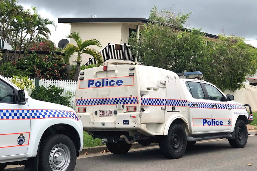 Police cars parked outside a two-storey apartment block