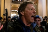 A protester yells at Michigan State Police after protesters occupied the state capitol building
