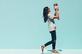 Woman with brown hair walking while holding her baby to depict what to do when you're fired on maternity leave.