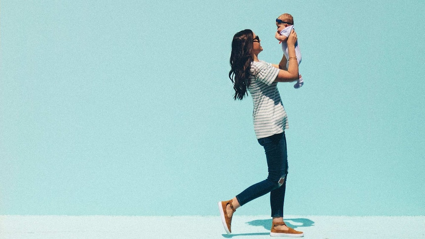 Woman with brown hair walking while holding her baby to depict what to do when you're fired on maternity leave.